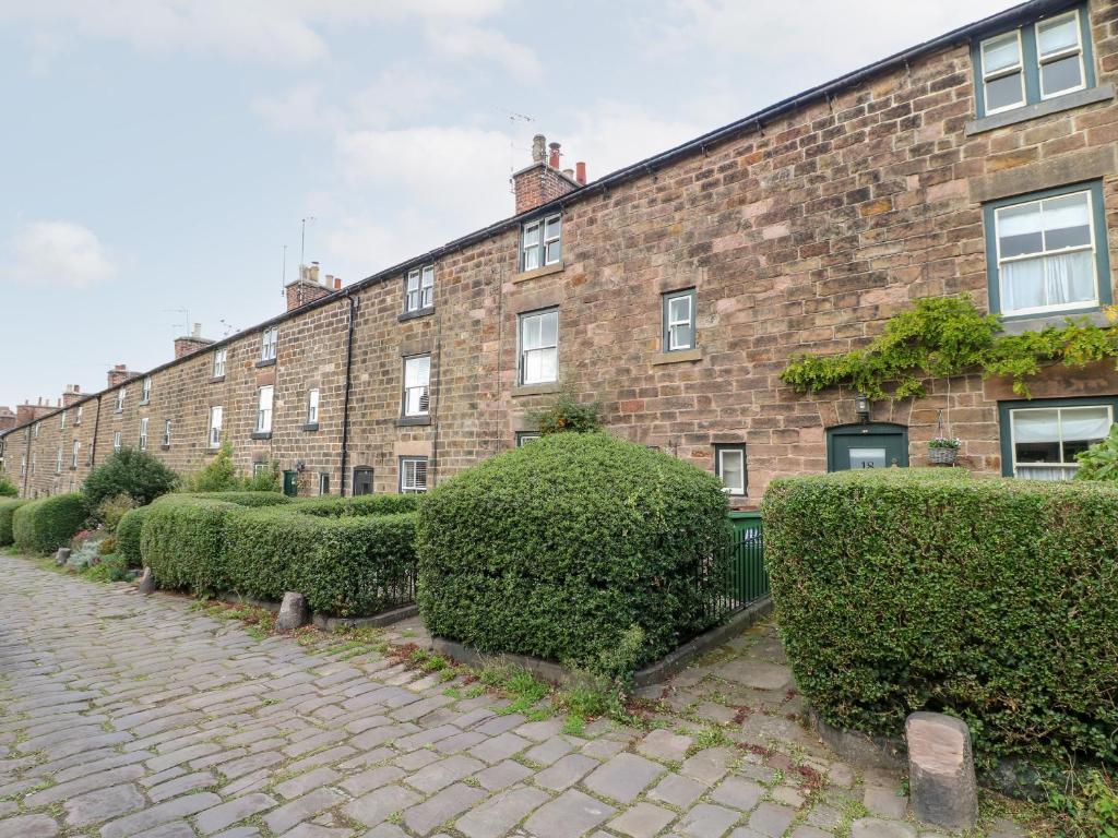 a brick building with a row of bushes in front of it at 16 Long Row in Belper