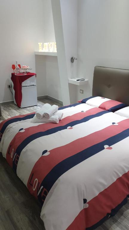 een bed met een rode witte en blauwe deken bij Le Volte Apartments in Torchiarolo