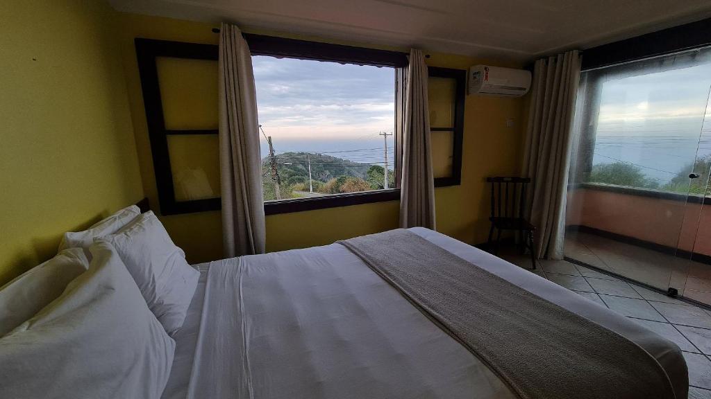 a bedroom with a bed and a large window at Pousada Mirante dos Papagaios in Búzios