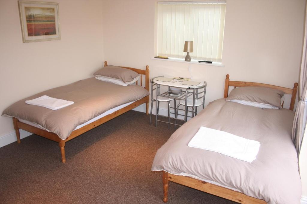 two beds in a room with a small table at Twin Bays in Hedon