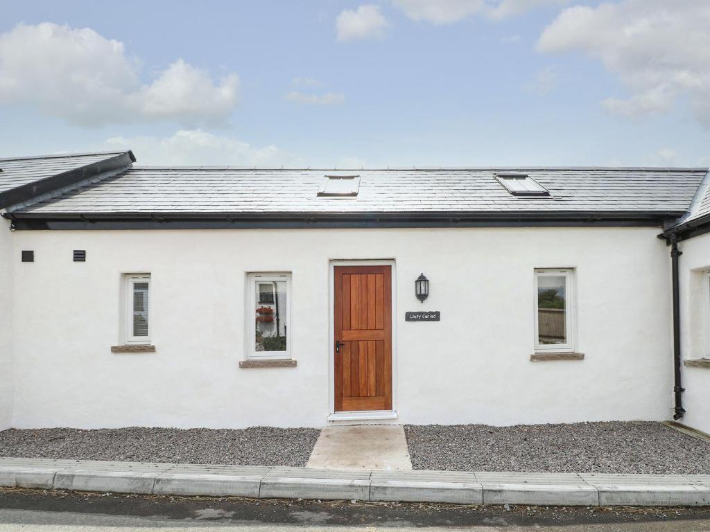 a white house with a wooden door at Llety Cariad - 2 Plough & Harrow in Cowbridge