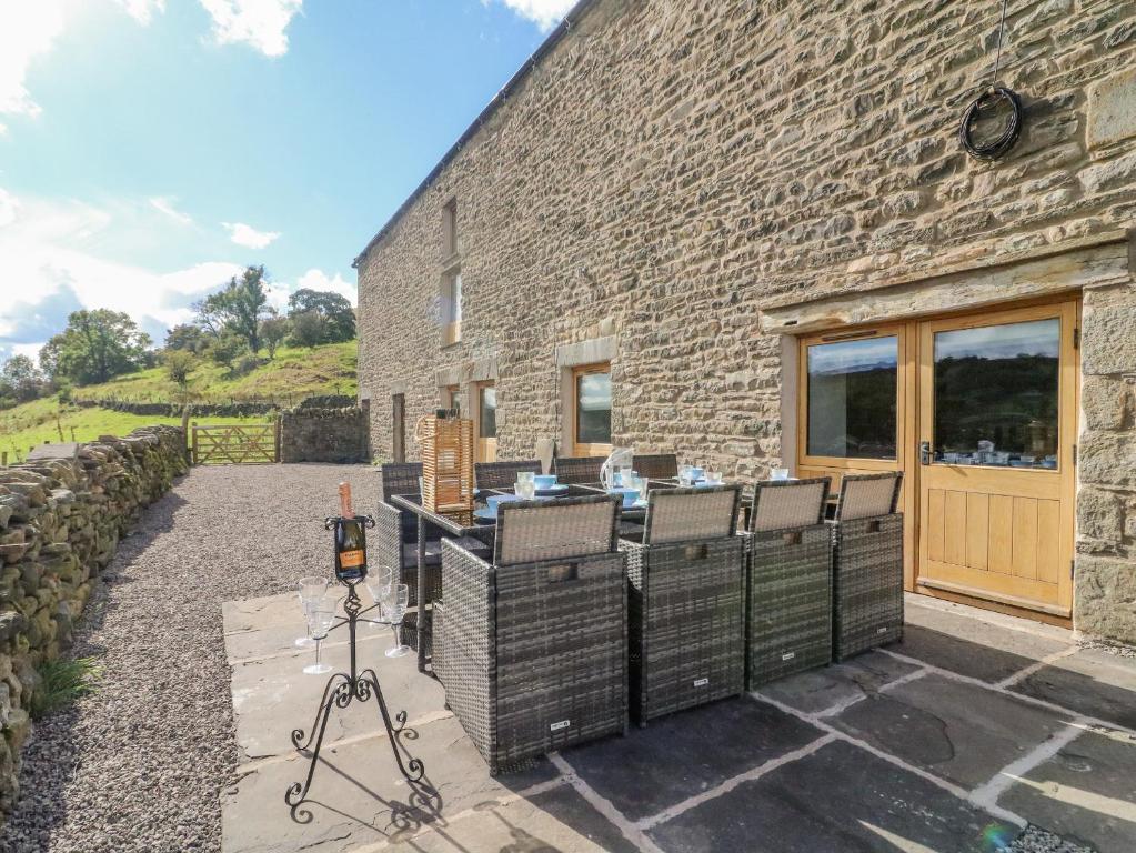 a stone house with a table and chairs outside at Hollowgill Barn in Sedbergh