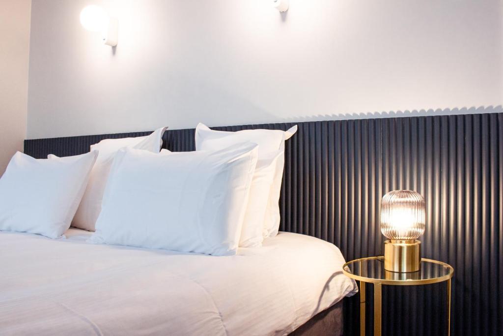a bed with white pillows and a table with a lamp at Le Gamaritz in Biarritz