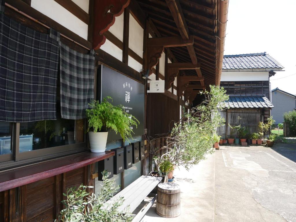 un edificio con un porche con macetas. en 駅前宿舎 禪 shared house zen en Eiheiji