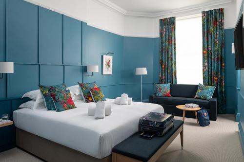 a blue bedroom with a large bed and a couch at The Goodenough Hotel London in London