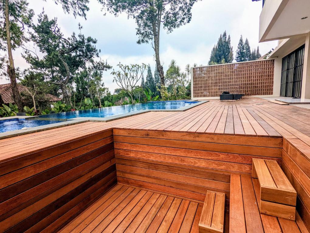 a wooden deck with a swimming pool and benches at Cottonwood Exclusive Villa @Lembang Asri - Jacuzzi Playground Netflix Billyard in Lembang