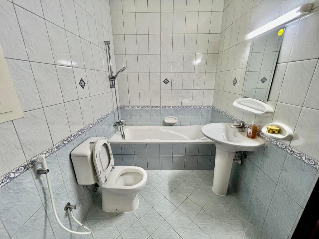 a bathroom with a toilet and a sink and a tub at Robin Hostel Dubai in Dubai