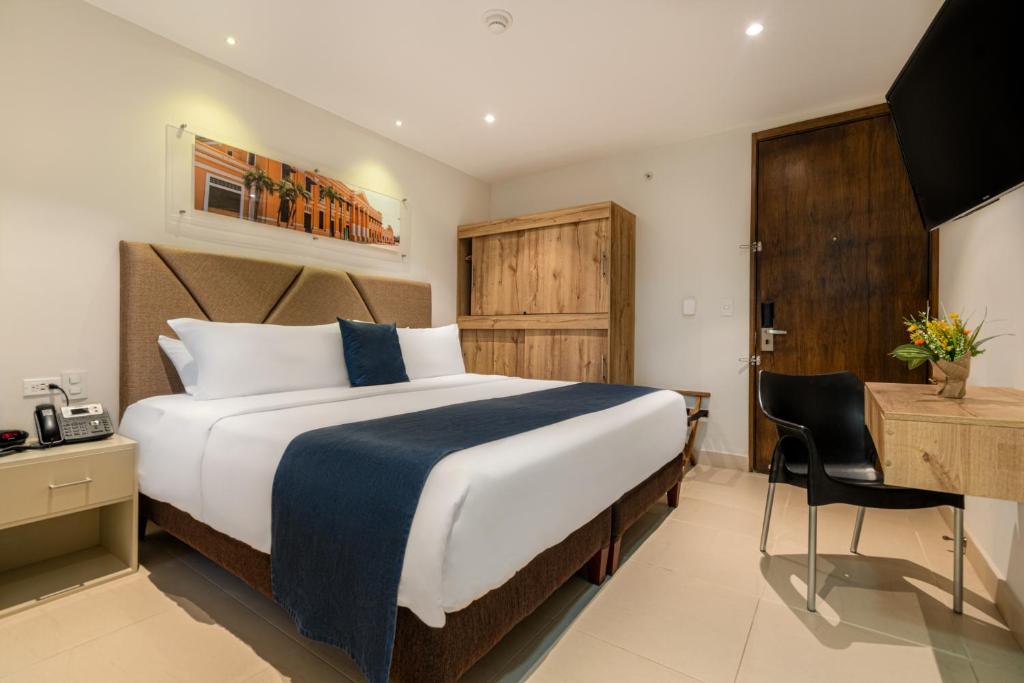 a hotel room with a large bed and a desk at Hotel Portal del Río in Barranquilla