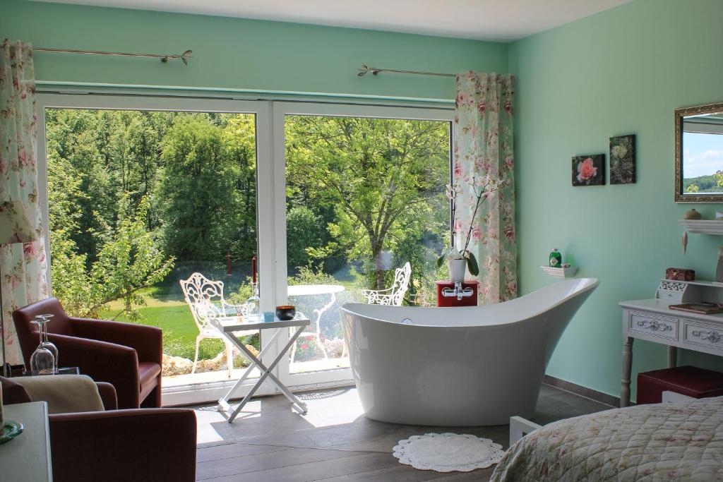 ein Bad mit einer Badewanne vor einem Fenster in der Unterkunft Hotel Haus Kallenberg in Herbrechtingen
