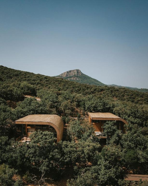 a building in the middle of a hill with trees at Souki ~ Lodges & Spa in Cabrières
