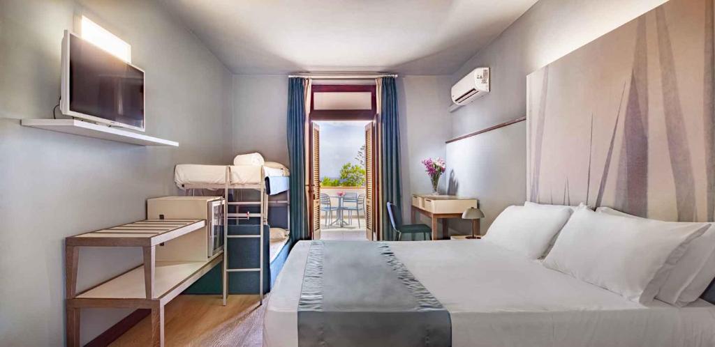 a bedroom with a bed and a desk and a window at Hotel Baia Imperiale in Campo nell'Elba