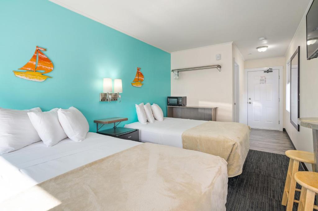two beds in a hotel room with blue walls at Beach Bum Inn in Ocean City