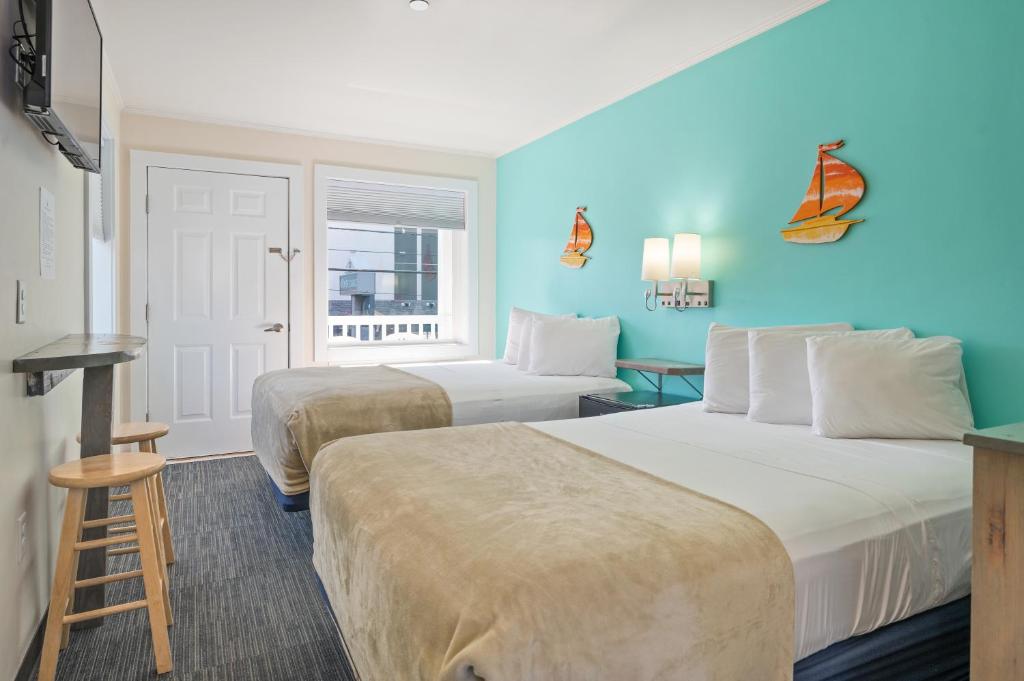 two beds in a hotel room with blue walls at Beach Bum Inn in Ocean City