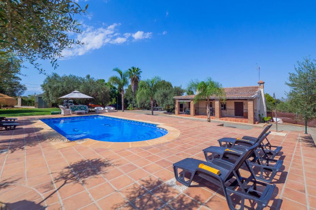 a patio with chairs and a swimming pool at Cubo's Finca Los Acebuches in Alhaurín el Grande