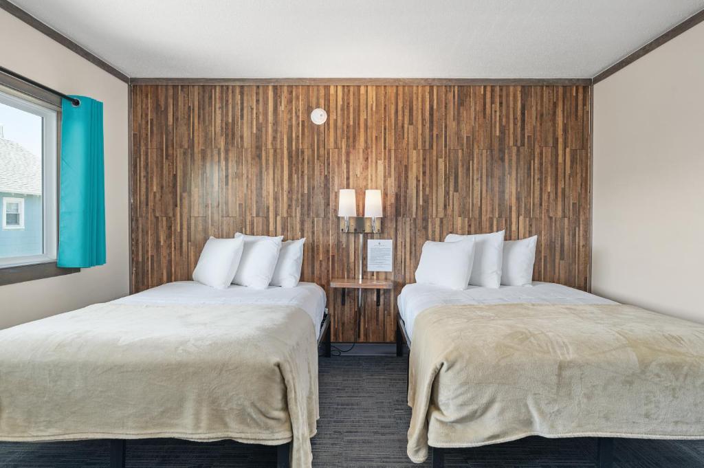 two beds in a hotel room with wood paneling at Beach Bum Inn in Ocean City