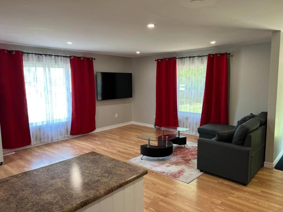 sala de estar con cortinas rojas y sofá en ENTIRE 2-BEDROOM TOWNHOUSE ON a RUSTIC FARM - A, 