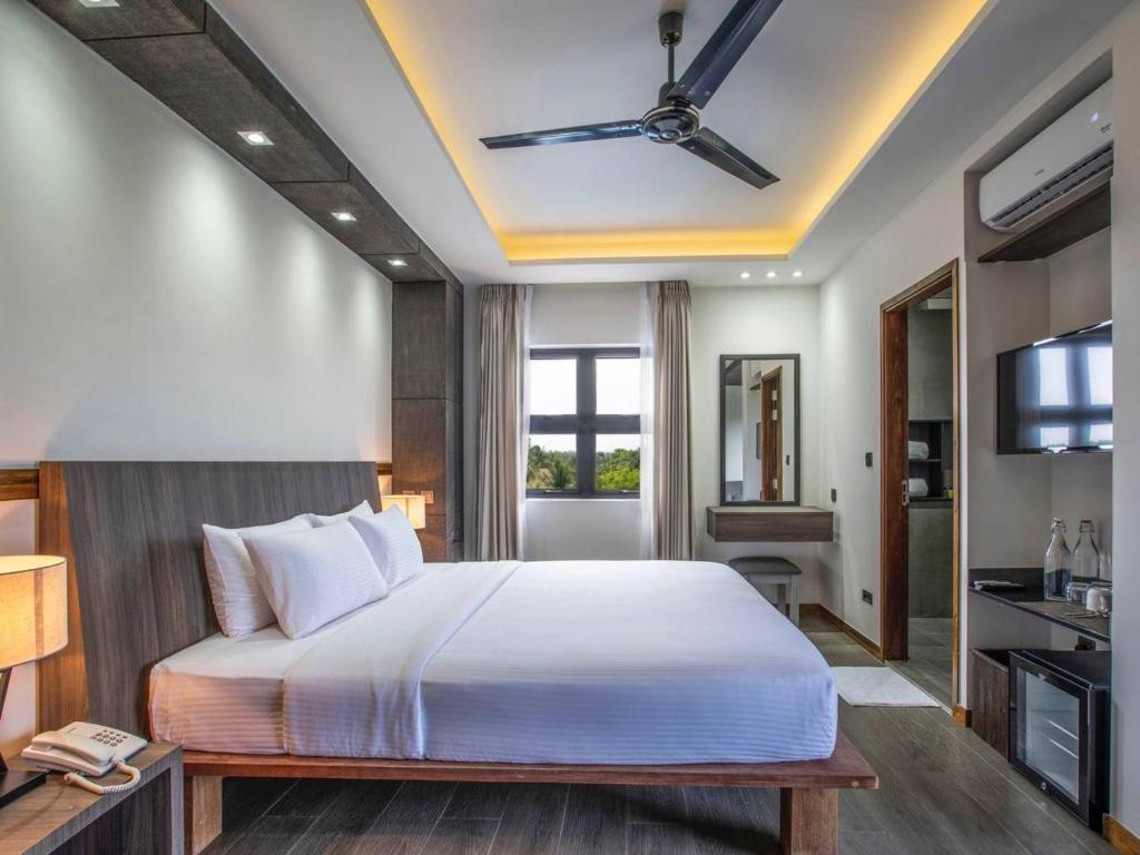 um quarto com uma cama grande e uma televisão em Ataraxis Grand and Spa Fuvahmulah em Fuvahmulah