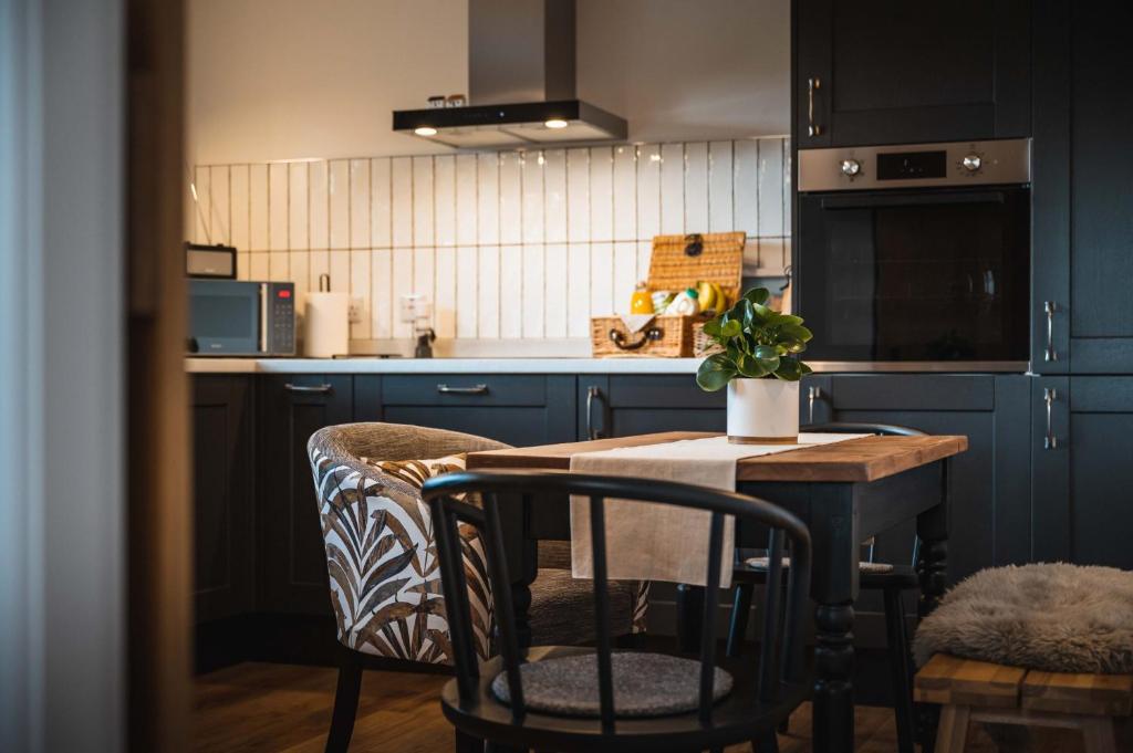uma cozinha com armários azuis e uma mesa e cadeiras em Drumdry em Wick