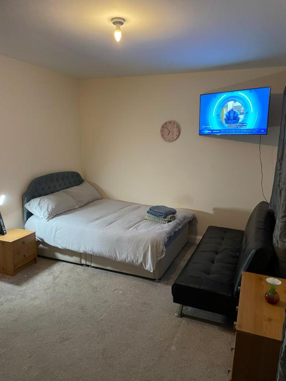 a bedroom with a bed and a couch and a flat screen tv at Private Rooms In A Cheerful 4-Bedroom Town House in Broughton