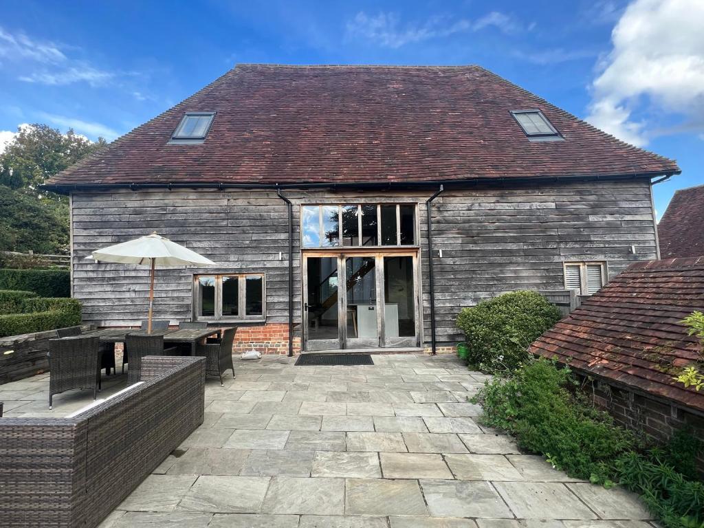 a house with an umbrella and a patio at Batts Barn in Edenbridge
