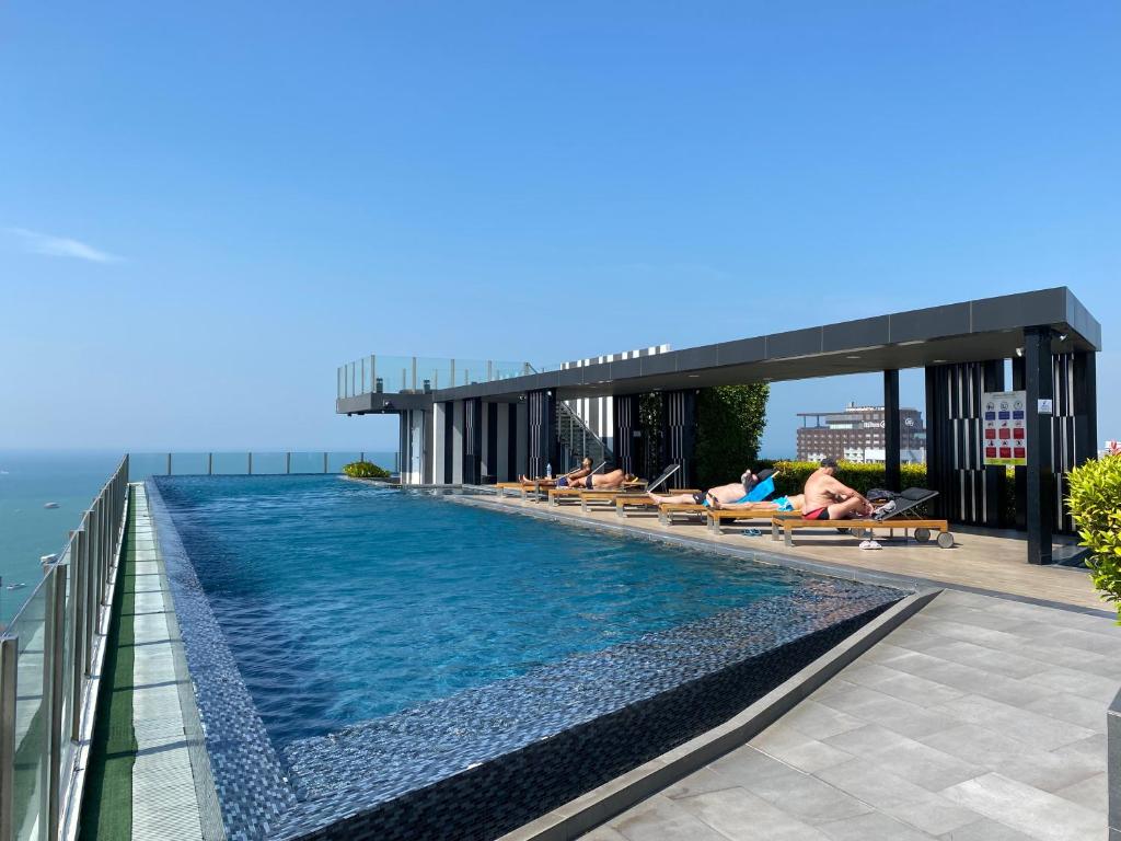 a pool on the roof of a building with people laying on chairs at The Base in pattaya in Pattaya Central