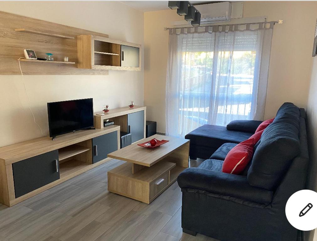 ein Wohnzimmer mit einem blauen Sofa und einem TV in der Unterkunft Adosado cerca de la playa y club de buceo con piscina en calabardina, Aguilas in Calabardina