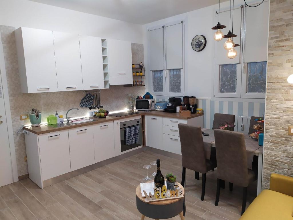 een keuken met witte kasten en een tafel met wijnflessen erop bij San Siro Dream Home -Apartment with garage-Milano in Milaan