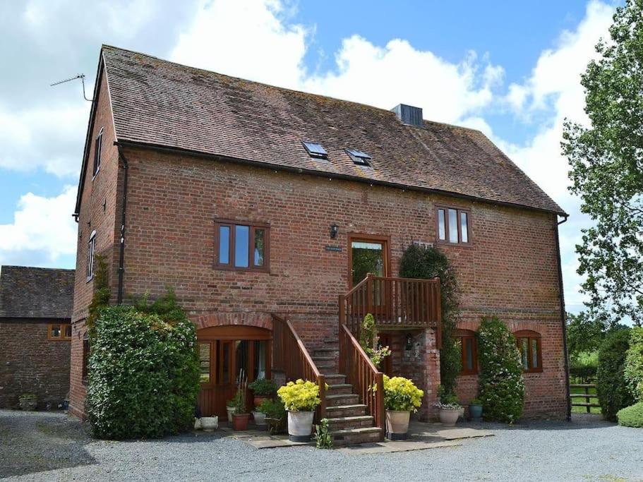 a brick house with a staircase in front of it at The Oast House - farm stay apartment set within 135 acres in Bromyard