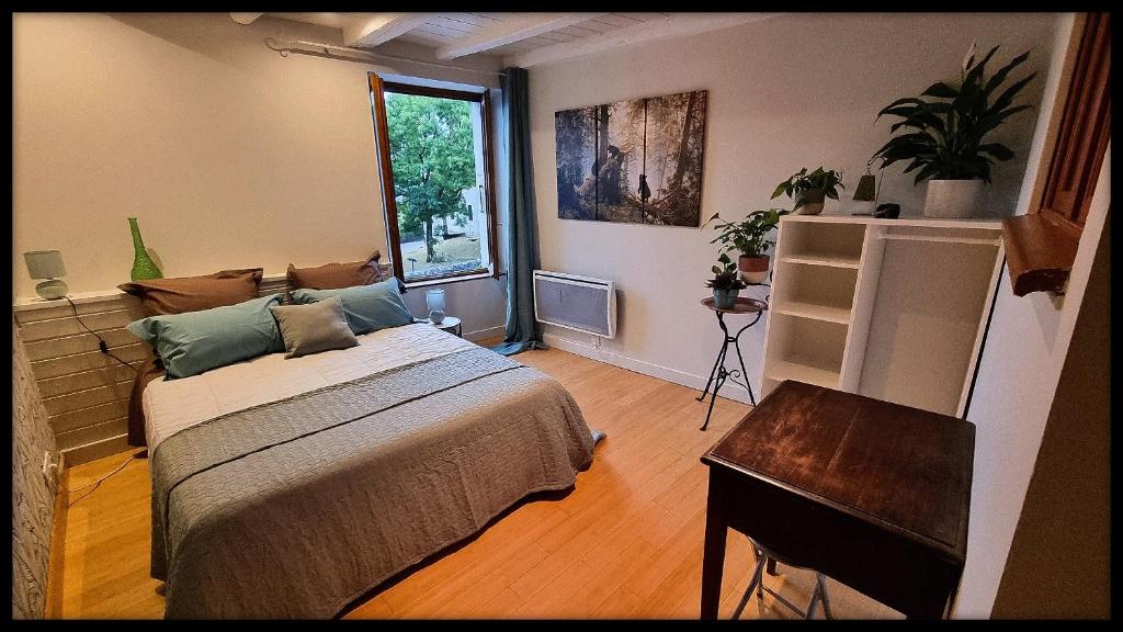 sypialnia z łóżkiem, stołem i oknem w obiekcie Ours-Les Jardins de Kuz w mieście Bernin