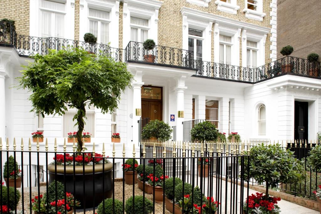 a white house with a fence and flowers at Beaufort House - Knightsbridge in London