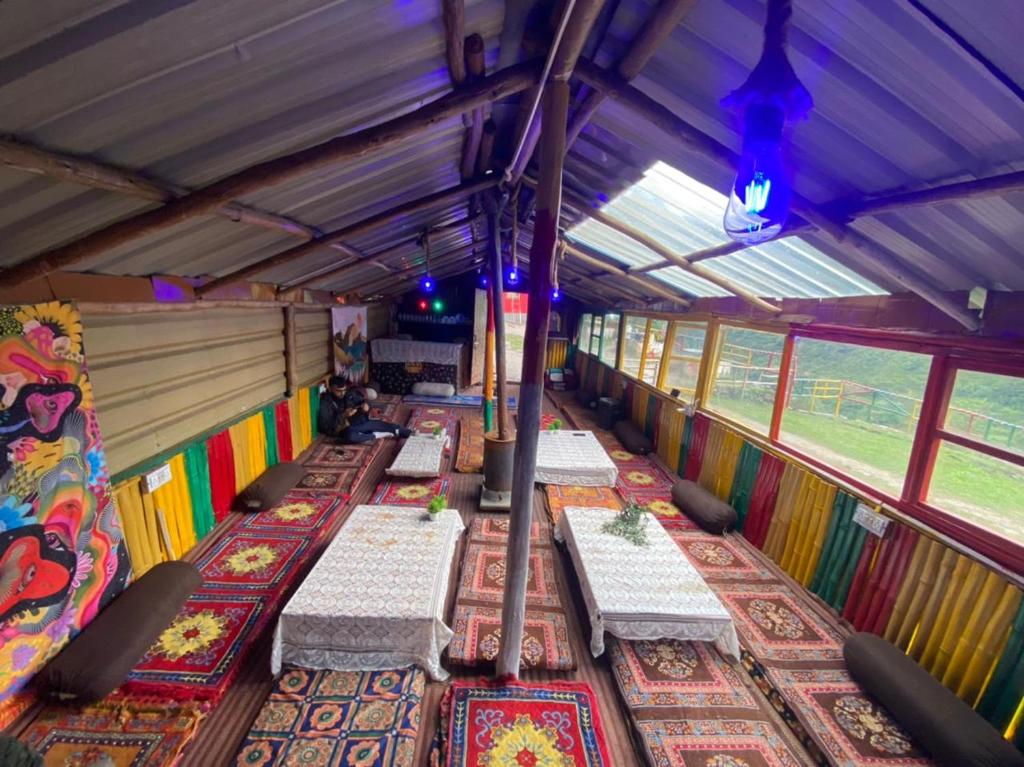 a row of tables in a bus with colorful rugs at Cafe Him, Tosh in Kalgha