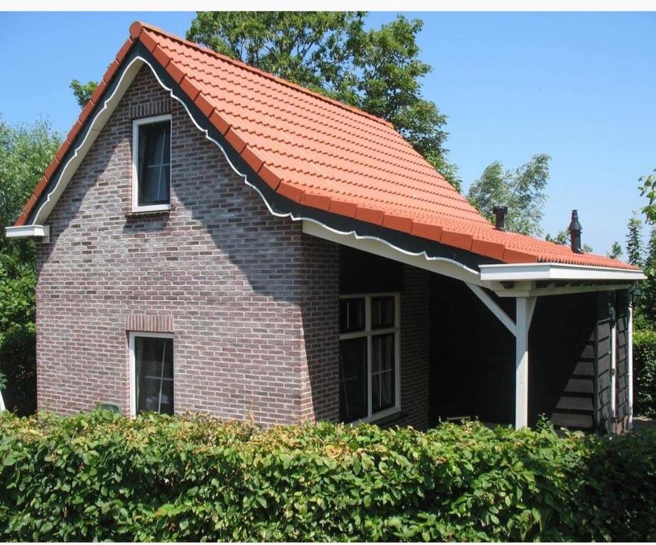 スロースケルケにあるVakantiewoning de Boshoornの小さな煉瓦造りのオレンジ色の屋根の家