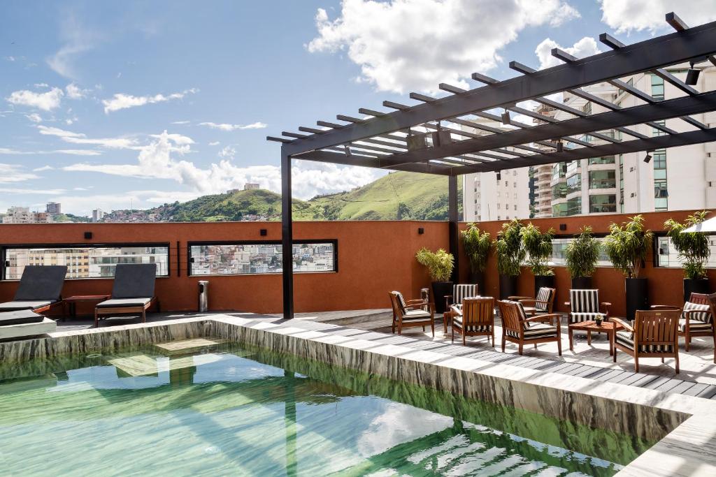 a swimming pool on the roof of a building with tables and chairs at Victory Business Hotel in Juiz de Fora