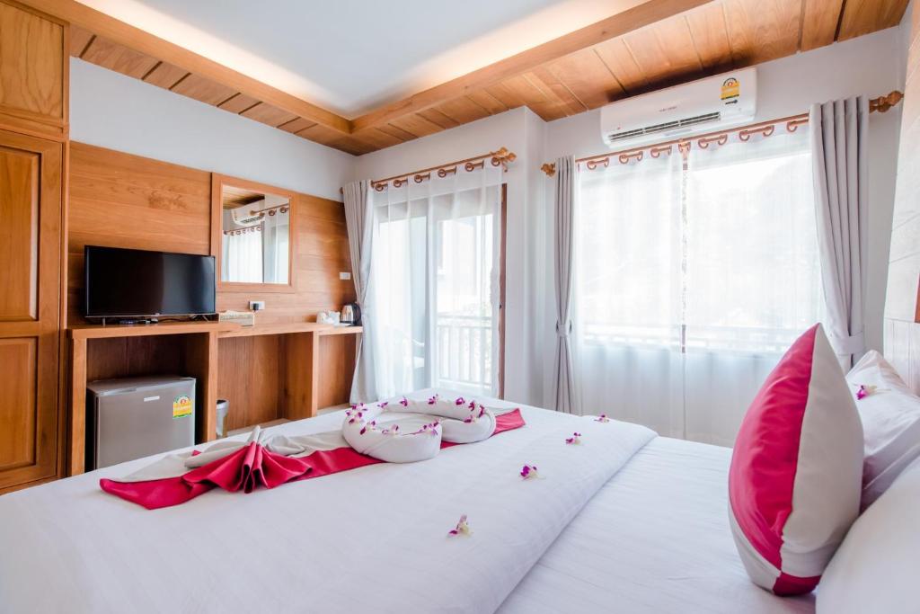 ein Schlafzimmer mit einem großen weißen Bett mit roten Kissen in der Unterkunft Lanta Ray Bay Hotel in Ko Lanta