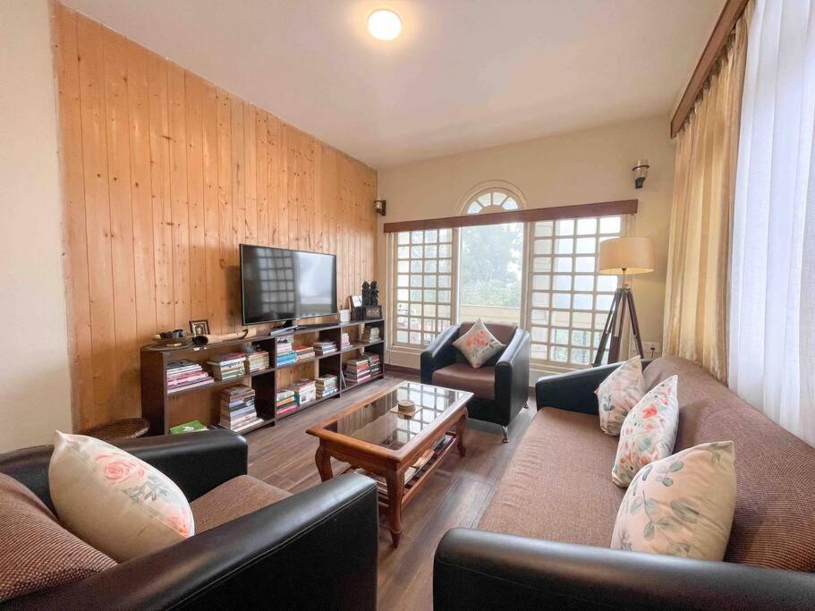 ein Wohnzimmer mit zwei Sofas und einem Fernseher in der Unterkunft Daphne House in Darjeeling
