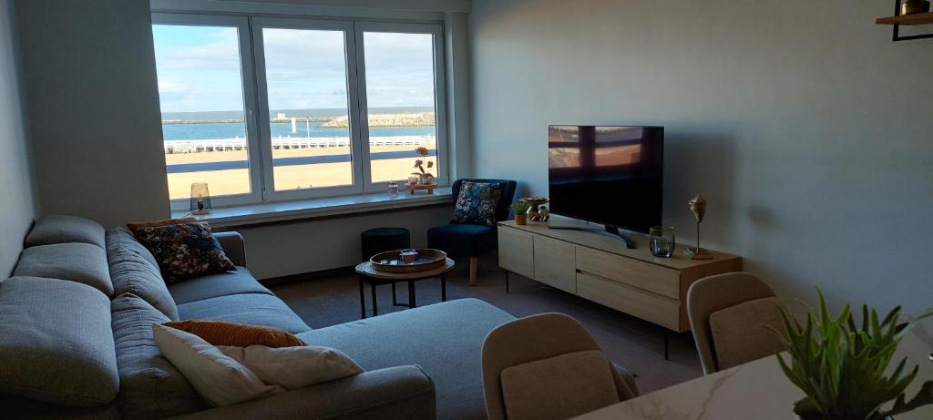 a living room with a couch and a flat screen tv at Vakantie-appartement La Régence @ Oostende in Ostend