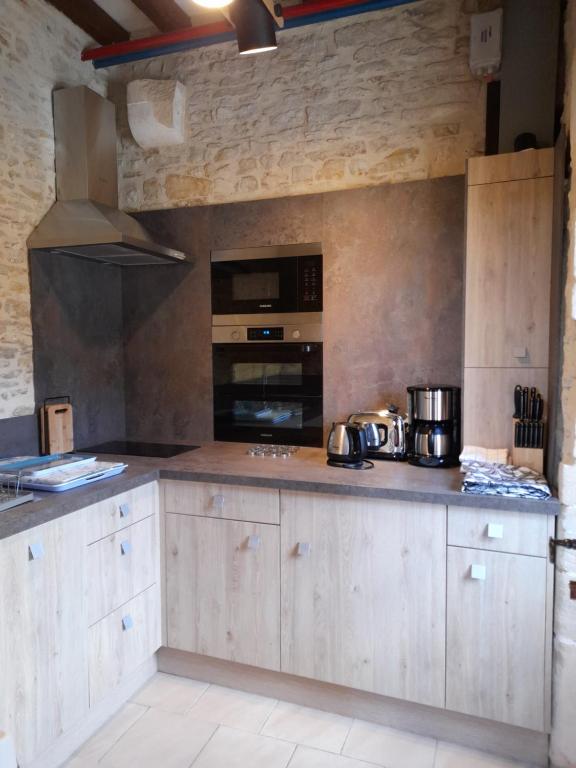 Una cocina con gabinetes de madera y un horno de estufa. en Chambres Résidentielles avec cuisine au Manoir de Mathan à Crépon 5 mn D'Arromanches et 10 mn de Bayeux, en Crépon