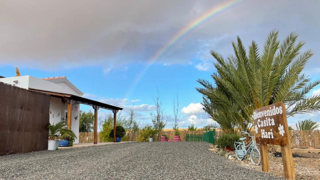 een regenboog in de lucht boven een huis met een bord bij Casita Hari, donde tu y tu tiempo se detienen. in Tuineje