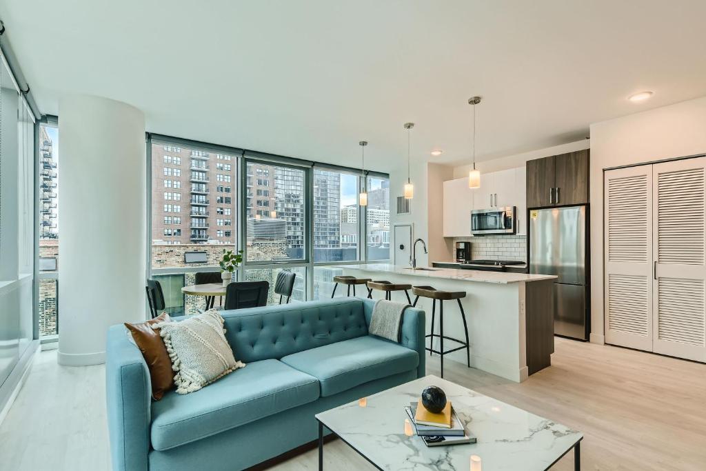 a living room with a blue couch and a kitchen at Sentral Michigan Avenue in Chicago