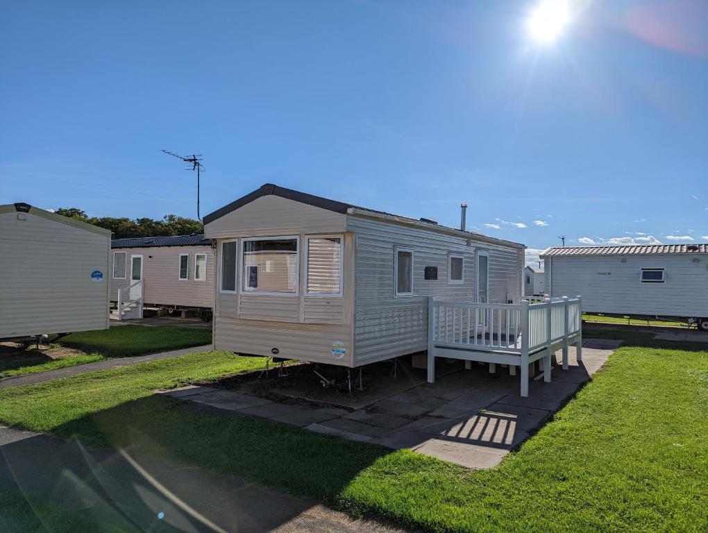 a mobile home in a yard with a porch at The Jones's Family Caravan with private decking - Presthaven in Prestatyn