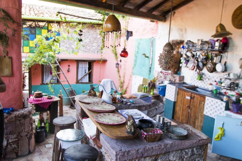 uma cozinha com uma mesa e um balcão com pratos em CASA DE RETALHOS Boutique Albergue, casaril histórico, com 5 suítes individuais e cozinha coletiva, no coração da vila de Igatu-Ba, que preserva fortes traços culturais da época do garimpo, venha viver uma experiência única! em Igatu