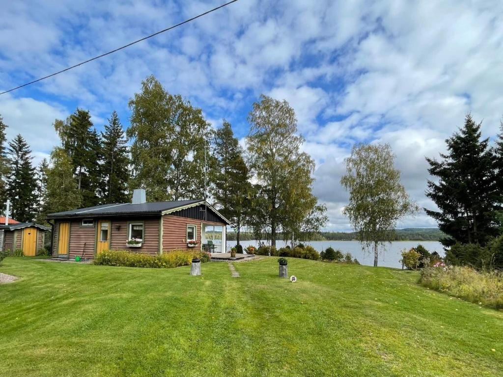 a house on a lawn with a lake in the background at 4 person holiday home in STORFORS in Storfors