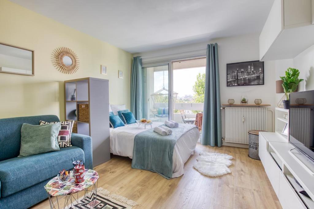 Una sala de estar con una cama y un sofá azul. en Super appartement avec vue sur la Tour Eiffel, en Le Kremlin-Bicêtre