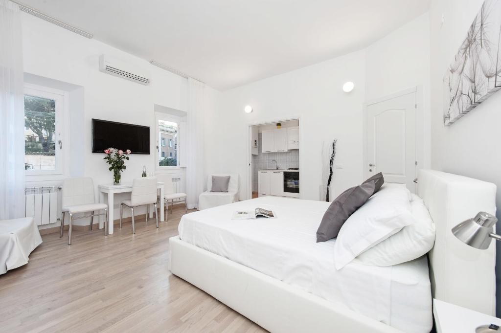 una camera bianca con un letto bianco e una sala da pranzo di White Flat Colosseo a Roma