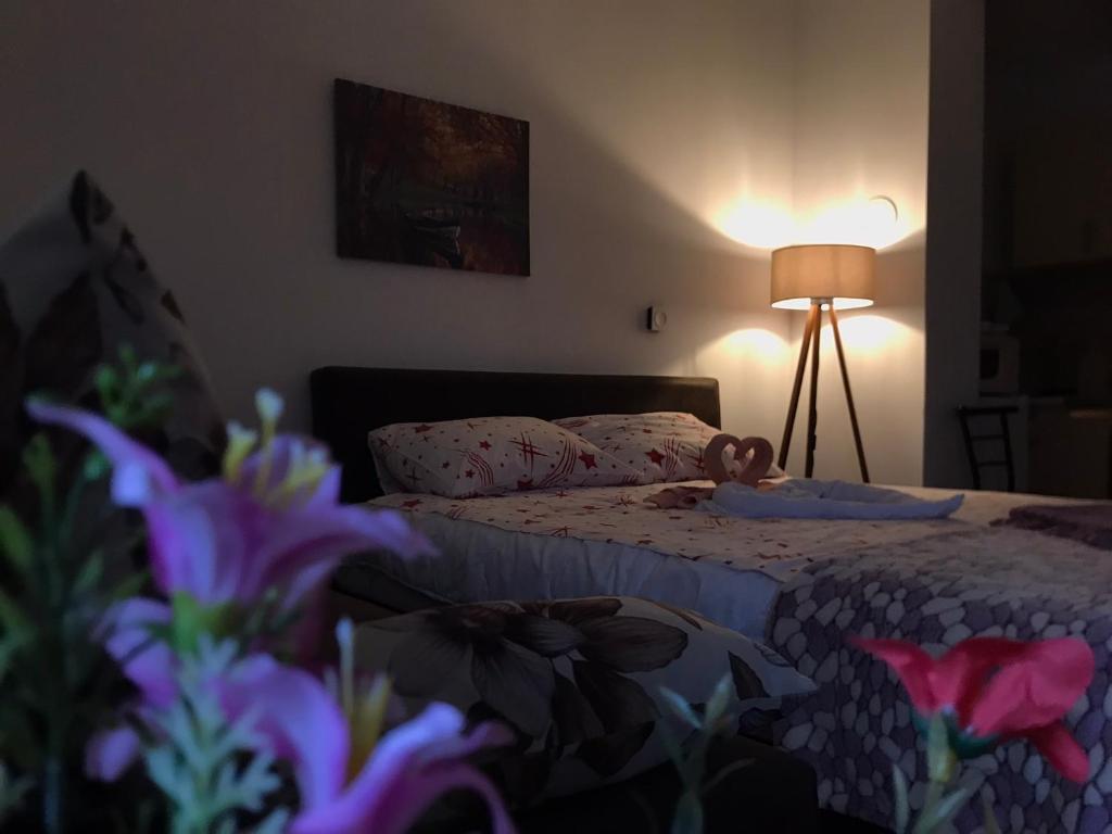 - une chambre avec un lit, une lampe et des fleurs dans l'établissement apartman stan na dan Sarajevo EMA, à Sarajevo