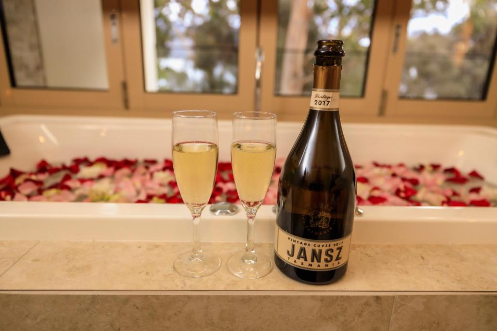 two glasses of white wine next to a bottle of champagne at Bruny Island Oceanfront Luxe Cabin with Spa in Adventure Bay