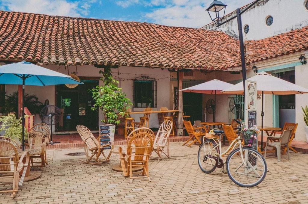eine Terrasse mit Stühlen und Tischen sowie ein Fahrrad, das vor einem Gebäude geparkt ist in der Unterkunft Pueblito Magico Hostel - Mompox in Mompos