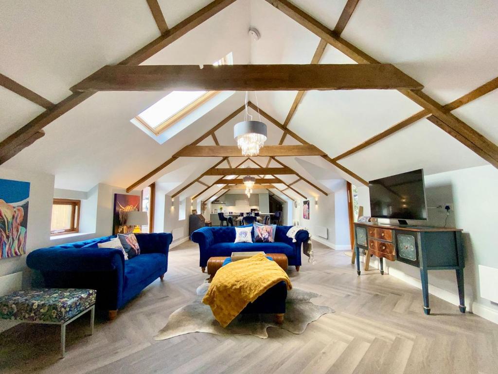 a living room with blue couches and a ceiling with beams at The Stables in Yate