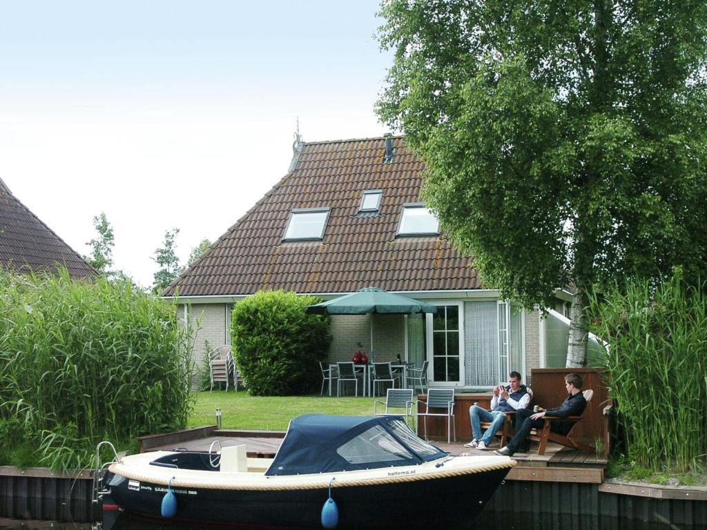 zwei Personen sitzen auf einer Veranda eines Hauses mit einem Boot in der Unterkunft Lush holiday home in Earnew ld in Earnewâld