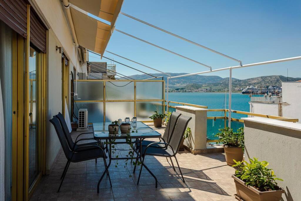 a patio with a table and chairs on a balcony at Cozy seaside penthouse with sea & mountain view. in Volos